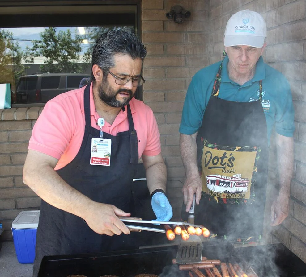 Alejandro Cuellar, left, and Dennis Walto cook hot dogs and hamburgers for the staff in Douglas on Tuesday. Bruce Whetten Herald/Review